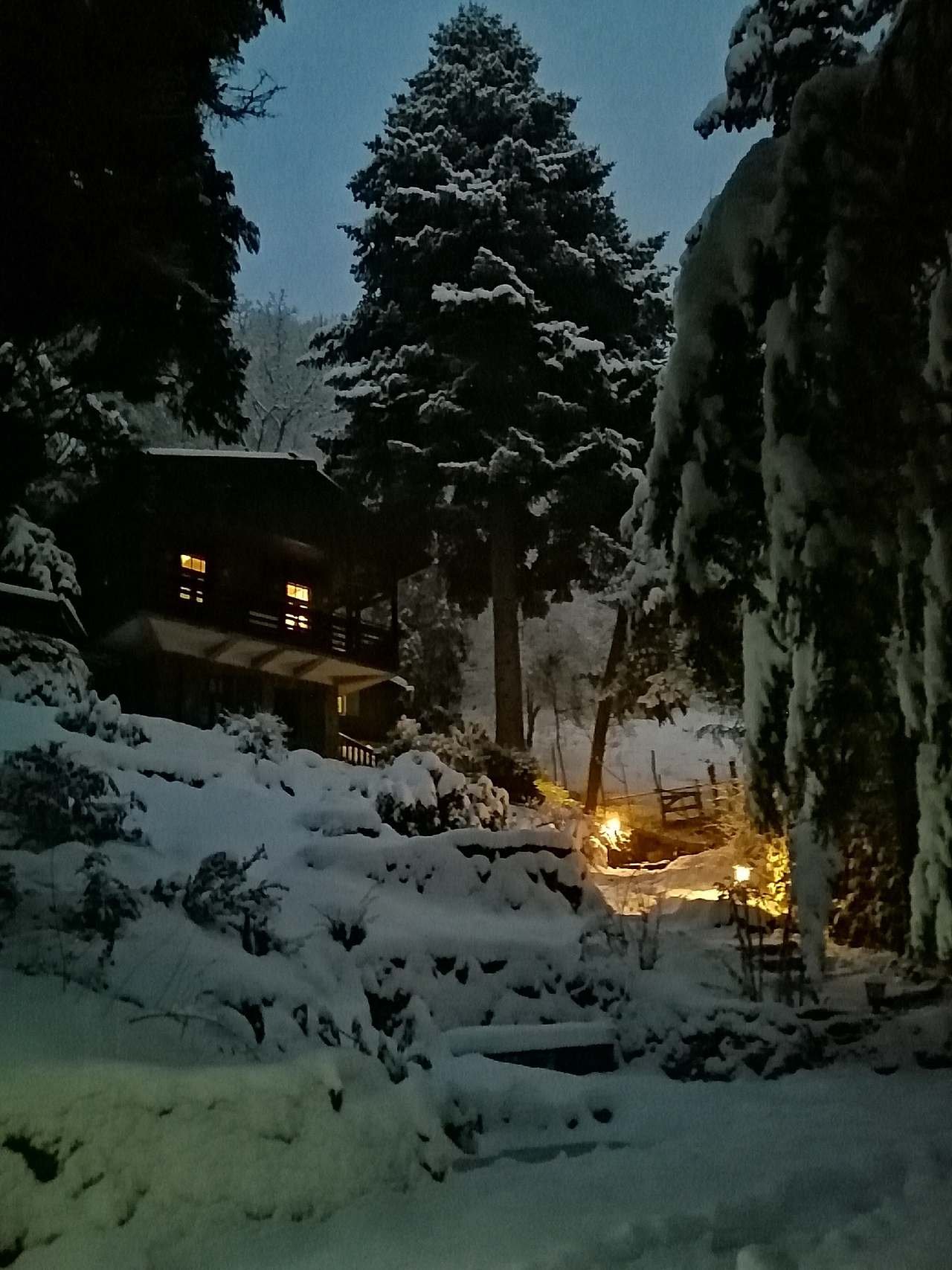Hájenka v zimě před setměním s rozsvícenými lucerničkami u cesty