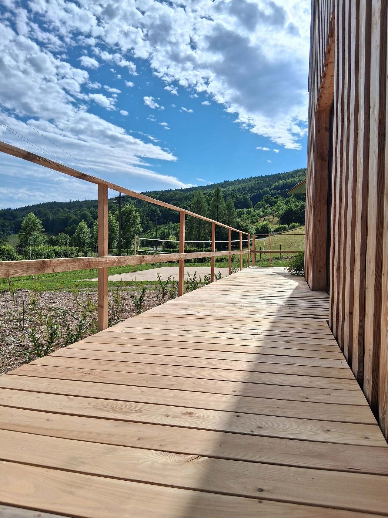 Obytná terasa (75 m2) dolní chaty. V pozadí volejbalové hřiště.