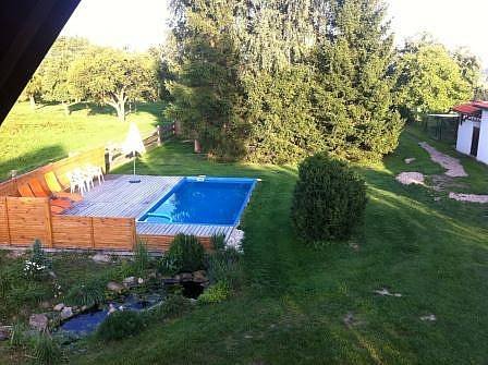 Pohled z balkonu na bazén a zahradu