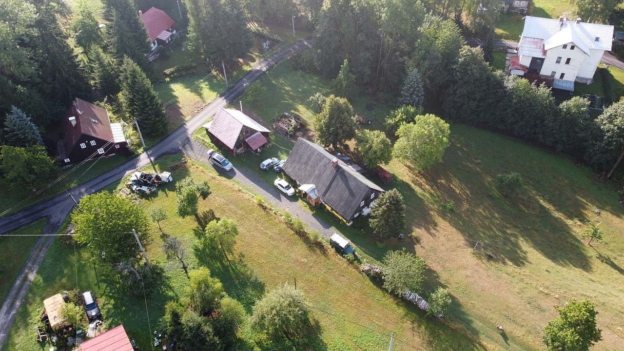 Stodola uprostřed, mezi roubenou chalupou majitele a silnicí