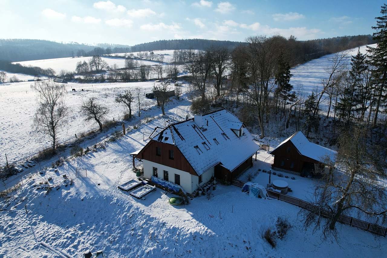 Zimní pohled na penzion a blízké okolí, v pozadí vrch Čeřínek